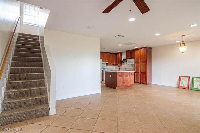 kitchen featuring sink, light tile patterned floors, an island with sink, ceiling fan, and decorative light fixtures