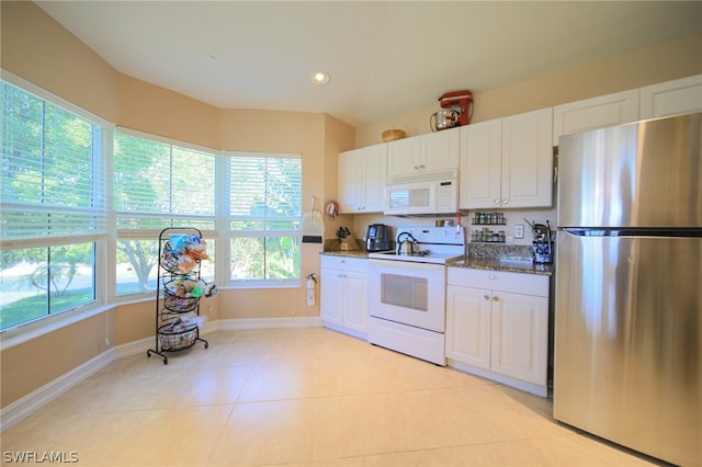 kitchen with white cabinets, a healthy amount of sunlight, white appliances, and dark stone counters