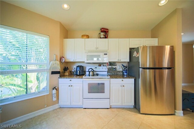 kitchen featuring white cabinetry, dark stone countertops, and white appliances