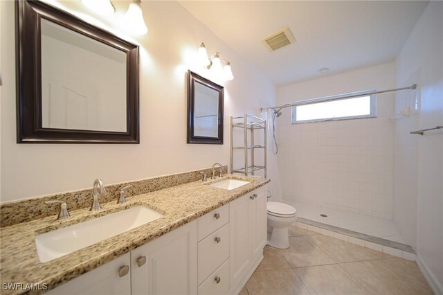 bathroom with tile patterned floors, toilet, vanity, and tiled shower