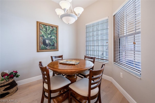 dining space with light wood-type flooring and an inviting chandelier