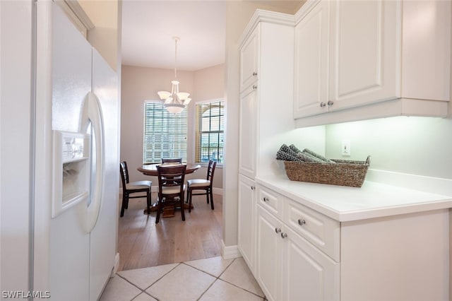 kitchen featuring hanging light fixtures, white cabinets, light tile patterned flooring, white fridge with ice dispenser, and an inviting chandelier