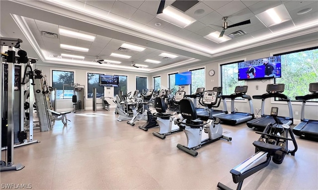 exercise room featuring ceiling fan, a drop ceiling, and a tray ceiling