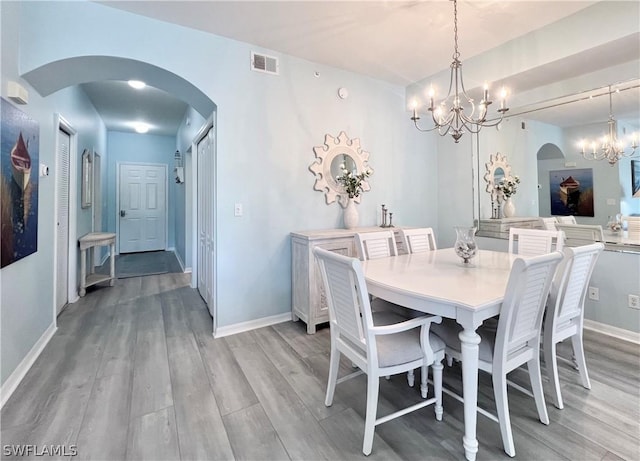 dining room with light hardwood / wood-style floors and an inviting chandelier