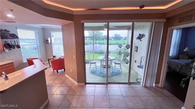 doorway to outside with light tile patterned flooring, ceiling fan, and a tray ceiling