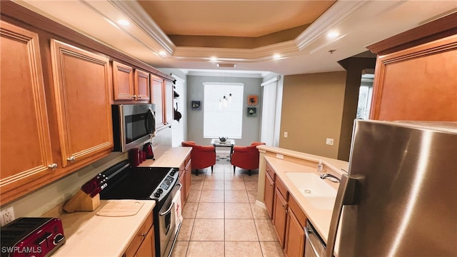 kitchen with light tile patterned flooring, a tray ceiling, stainless steel appliances, crown molding, and sink