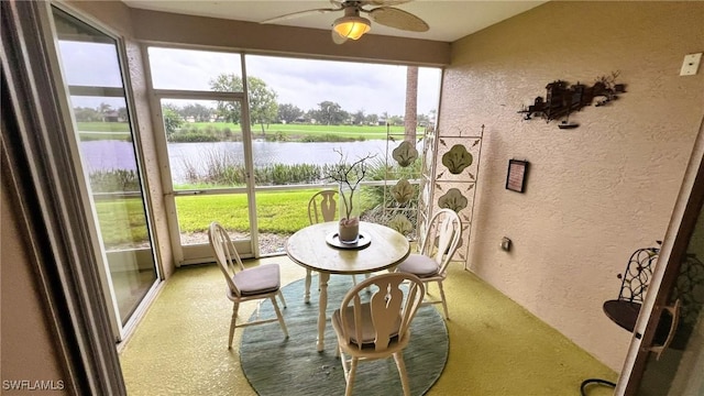 sunroom / solarium featuring ceiling fan, a healthy amount of sunlight, and a water view