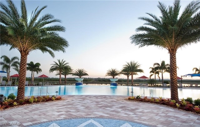 pool at dusk featuring a water view