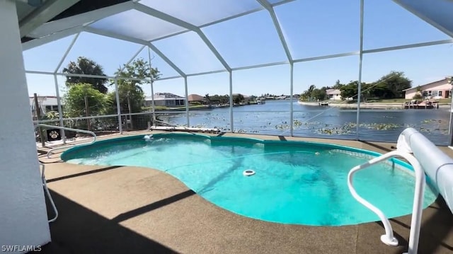 view of swimming pool with a patio area, glass enclosure, and a water view