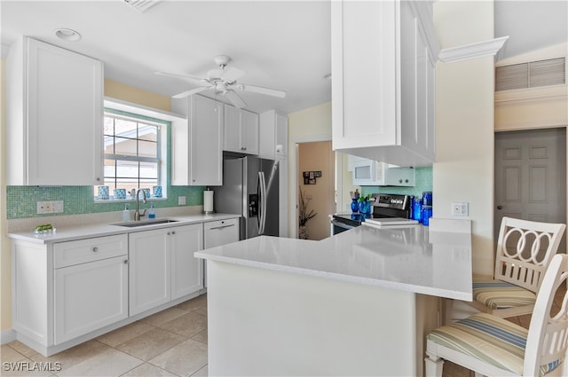 kitchen with appliances with stainless steel finishes, kitchen peninsula, white cabinetry, and sink