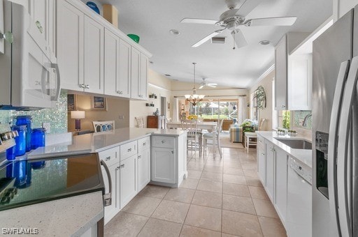 kitchen featuring kitchen peninsula, white cabinets, light tile patterned flooring, sink, and white appliances