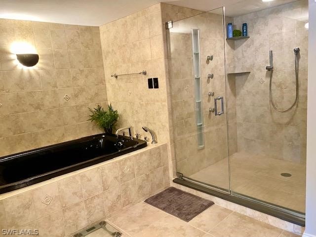 bathroom featuring a stall shower, a bath, and tile patterned floors