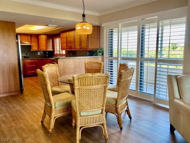 dining space featuring a healthy amount of sunlight, crown molding, and wood finished floors