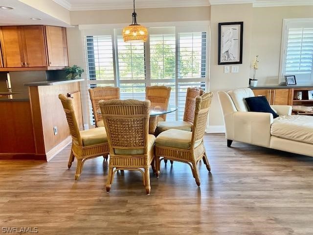 dining space with ornamental molding and wood finished floors