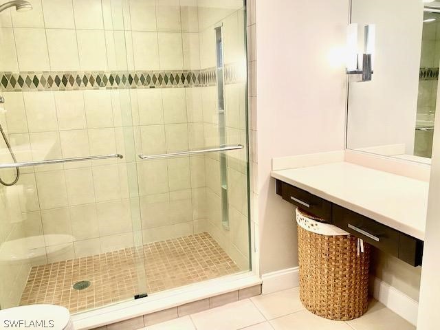 bathroom featuring a shower stall, toilet, and tile patterned floors