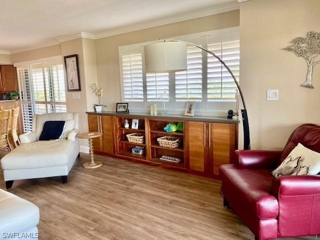 sitting room with hardwood / wood-style floors and crown molding