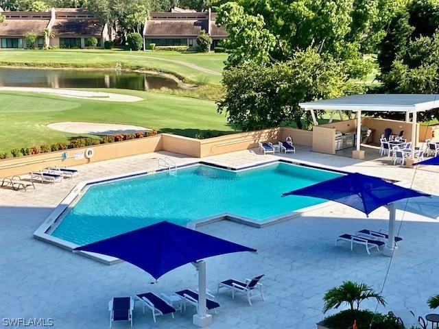 community pool featuring a patio area, a water view, golf course view, and a lawn