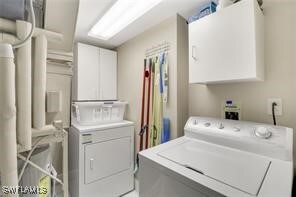 clothes washing area featuring cabinets and washing machine and clothes dryer