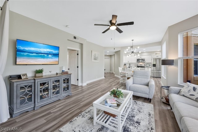 living room with ceiling fan with notable chandelier and hardwood / wood-style flooring