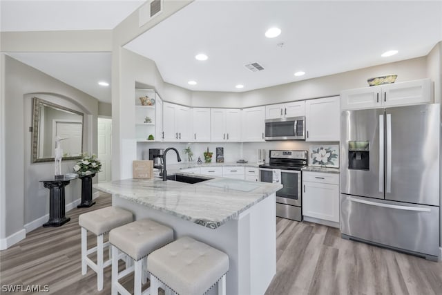 kitchen with sink, light stone countertops, appliances with stainless steel finishes, white cabinetry, and kitchen peninsula