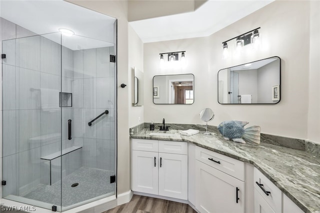 bathroom featuring vanity, a shower with shower door, and wood-type flooring