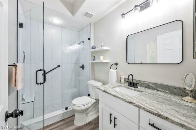 bathroom with hardwood / wood-style floors, vanity, an enclosed shower, and toilet