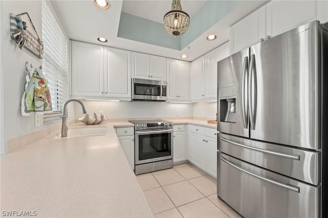 kitchen featuring sink, white cabinets, decorative light fixtures, light tile patterned floors, and appliances with stainless steel finishes