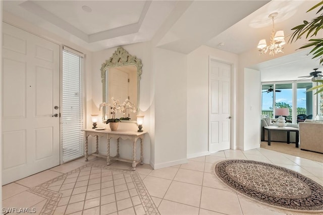 tiled foyer with a chandelier and a tray ceiling