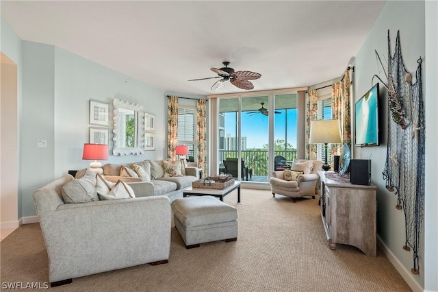 living room featuring ceiling fan, light carpet, and expansive windows