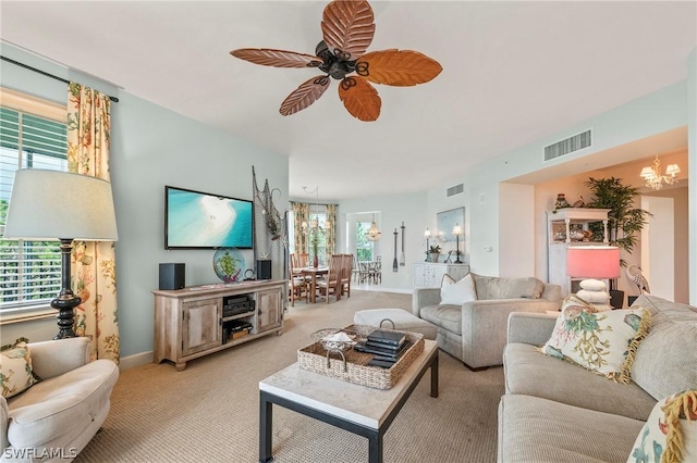 carpeted living room with ceiling fan with notable chandelier