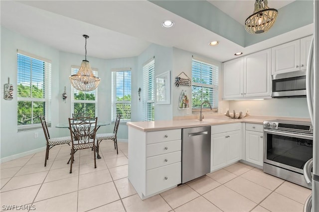 kitchen with hanging light fixtures, light tile patterned floors, an inviting chandelier, white cabinets, and appliances with stainless steel finishes