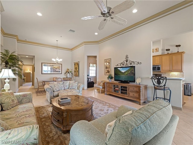 tiled living room with ceiling fan with notable chandelier, a towering ceiling, and crown molding