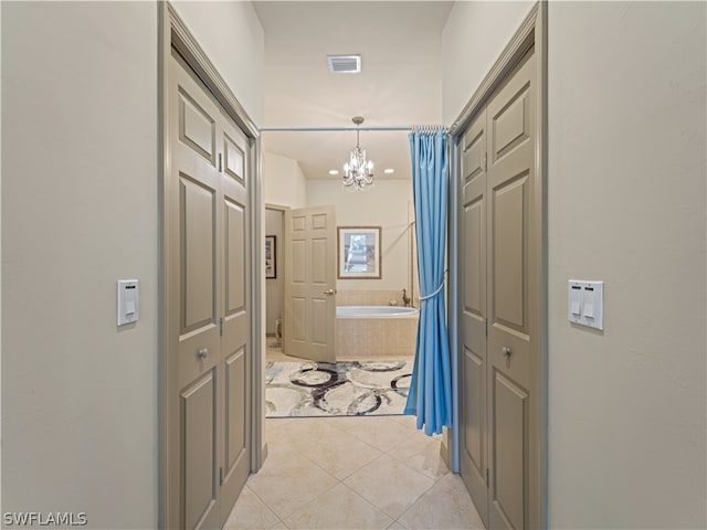 corridor with a notable chandelier and light tile patterned floors