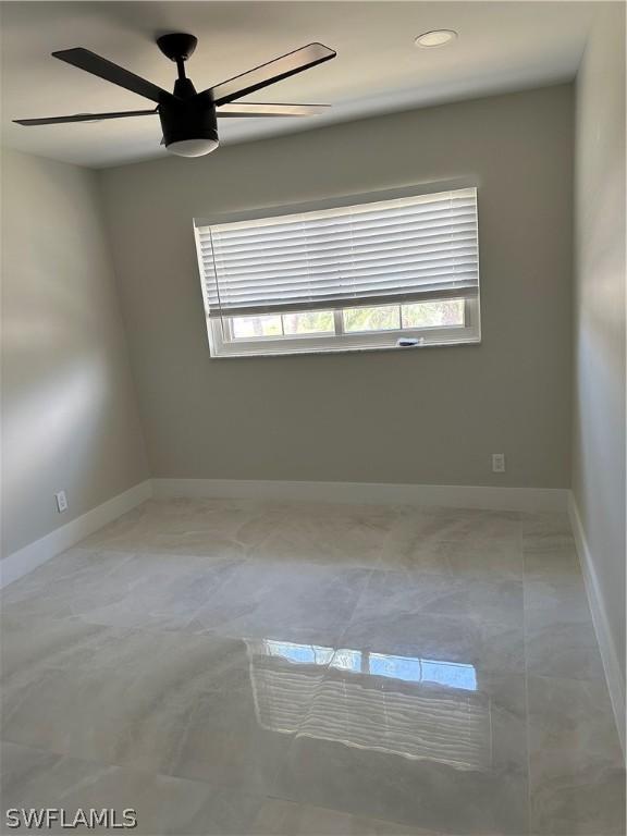 unfurnished room featuring a ceiling fan, plenty of natural light, and baseboards