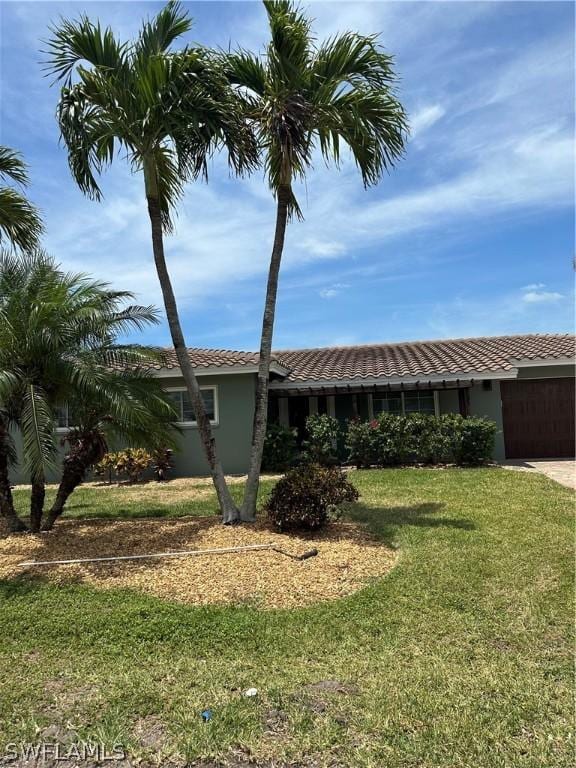 view of front of house with stucco siding, an attached garage, a tiled roof, driveway, and a front yard
