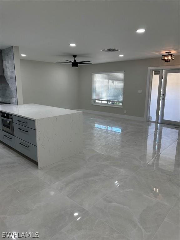 kitchen featuring visible vents, oven, marble finish floor, a ceiling fan, and open floor plan