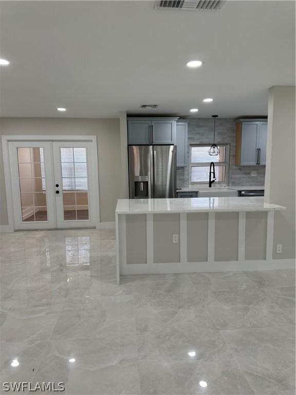 kitchen with light countertops, a sink, french doors, stainless steel fridge, and visible vents