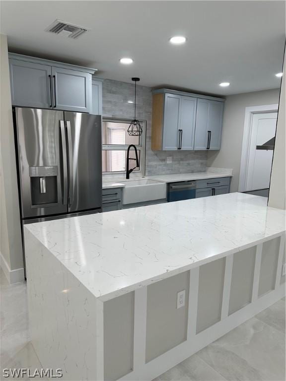 kitchen featuring a sink, stainless steel refrigerator with ice dispenser, light stone counters, and visible vents