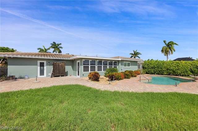 back of house featuring a patio, a fenced in pool, stucco siding, a tile roof, and a lawn