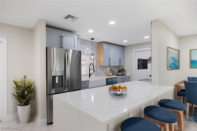 kitchen with visible vents, dishwasher, a breakfast bar, a sink, and stainless steel fridge with ice dispenser