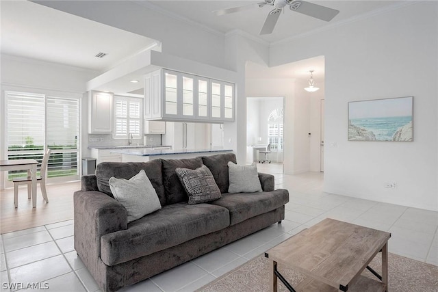 tiled living room with ceiling fan, ornamental molding, and sink