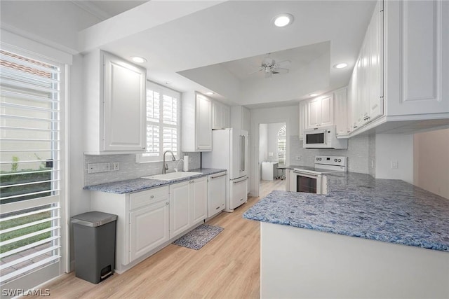 kitchen with white appliances, ceiling fan, sink, light hardwood / wood-style flooring, and white cabinets