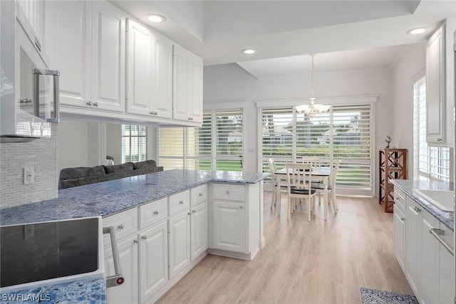 kitchen with kitchen peninsula, white cabinetry, plenty of natural light, and decorative light fixtures