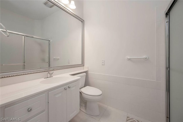 bathroom featuring walk in shower, tile patterned floors, toilet, vanity, and tile walls