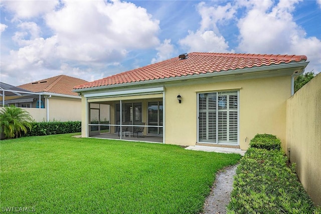 rear view of house with a sunroom and a lawn