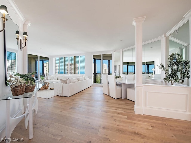 living room with expansive windows, light hardwood / wood-style flooring, ornamental molding, and decorative columns