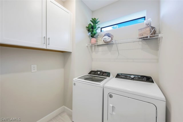 clothes washing area with washer and clothes dryer and cabinets