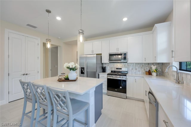 kitchen featuring white cabinetry, appliances with stainless steel finishes, sink, and a center island