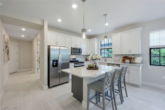 kitchen featuring a kitchen island, backsplash, white cabinets, and stainless steel appliances