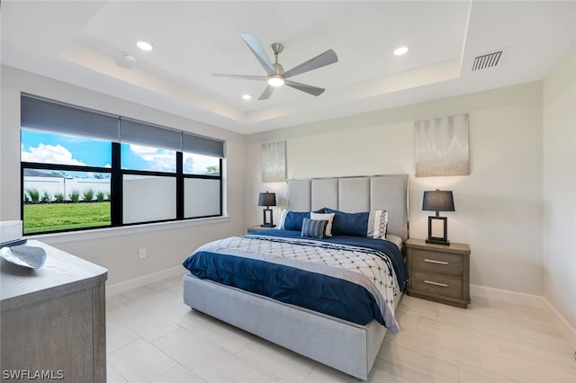 bedroom with ceiling fan and a tray ceiling